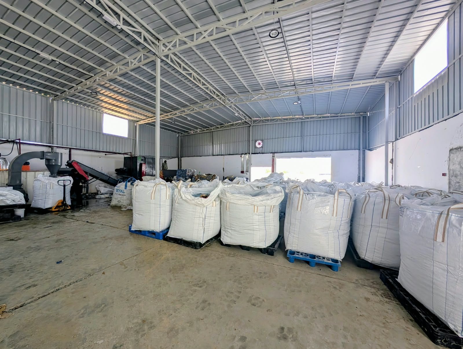 Industrial warehouse interior with rows of large white bulk storage containers lined up on concrete floor